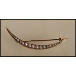 An early 20th Century stamped 15ct gold crescent brooch set with seed pearls, hinge pin with C clasp