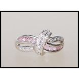 A stamped 375 9ct white gold crossover ring illusion set with white and pink accent stones. Weight