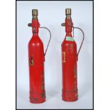 A pair of vintage 1950's fire extinguishers of tall cylindrical form having applied gold labels