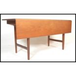 A 20th Century teak wood retro Danish dining table, the table with a single drop leaf raised on