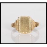 A 9ct gold signet ring having a stepped square head with scrolled decoration shoulders. Marks rubbed