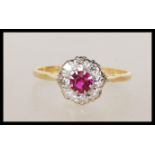 A vintage hallmarked 18ct yellow gold ring set with a central ruby with a halo of diamonds on a