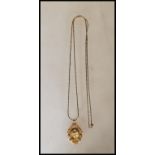 A unmarked 18ct gold Madonna pendant having scrolled decoration borders on a yellow metal chain.