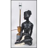 A vintage mid novelty 20th Century table lamp base in the form of a seated semi clad naked black