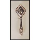 A continental silver baby's rattle of diamond shape form with central cockerel embossed decoration
