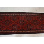 A Belgian Made ' Basra ' Tassled 'wool rug floor runner on red ground, central design of geometric