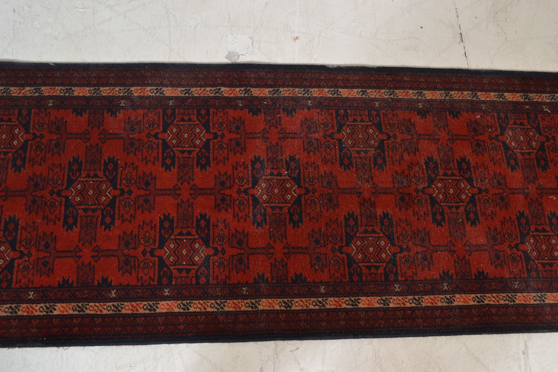 A Belgian Made ' Basra ' Tassled 'wool rug floor runner on red ground, central design of geometric