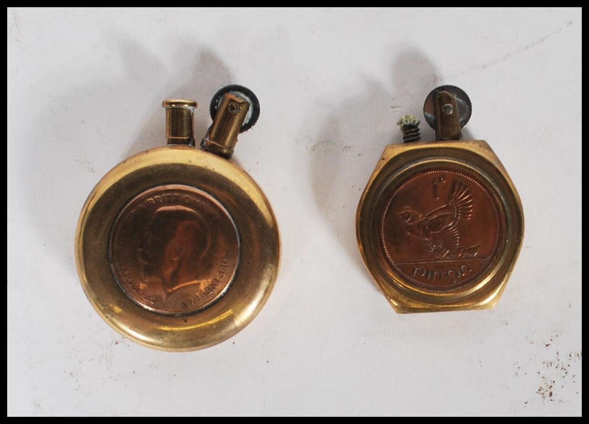 Two 20th Century military WW2 trench art brass lighters of round form one inset with a British coin,