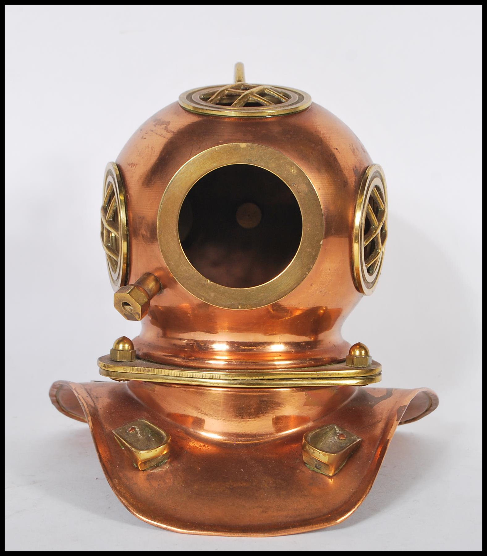 A vintage desktop model of an antique deep sea divers helmet having a copper body with brass