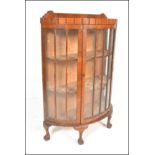 AQn early 20th Century Edwardian walnut Queen Anne revival demi-lune china display cabinet. Raised