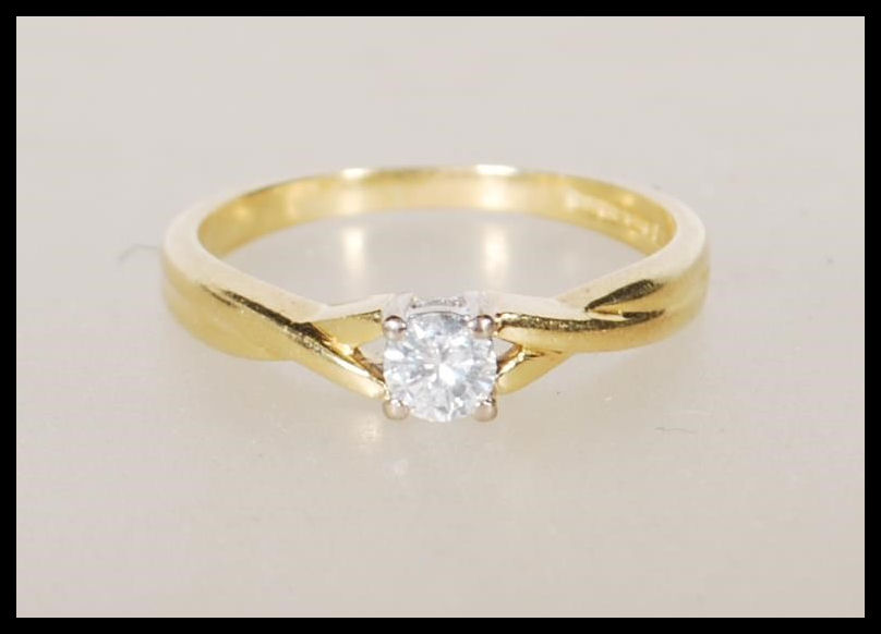 A hallmarked 18ct yellow gold solitaire diamond ring having decorative cross over shoulders with a