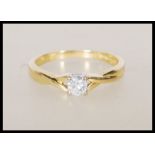A hallmarked 18ct yellow gold solitaire diamond ring having decorative cross over shoulders with a