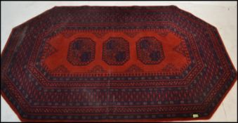 A 20th Century Persian style woolen floor rug on red ground of octagonal form, central panel with