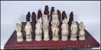 A large contemporary chess set heraldic style chess set and board in  resin with. The chess pieces