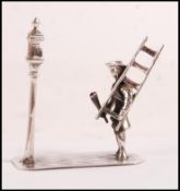 A sterling figurine depicting a lamplighter holder