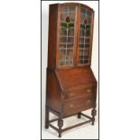 An early 20th Century oak bureau bookcase, leaded glass panel doors with adjustable shelves to the