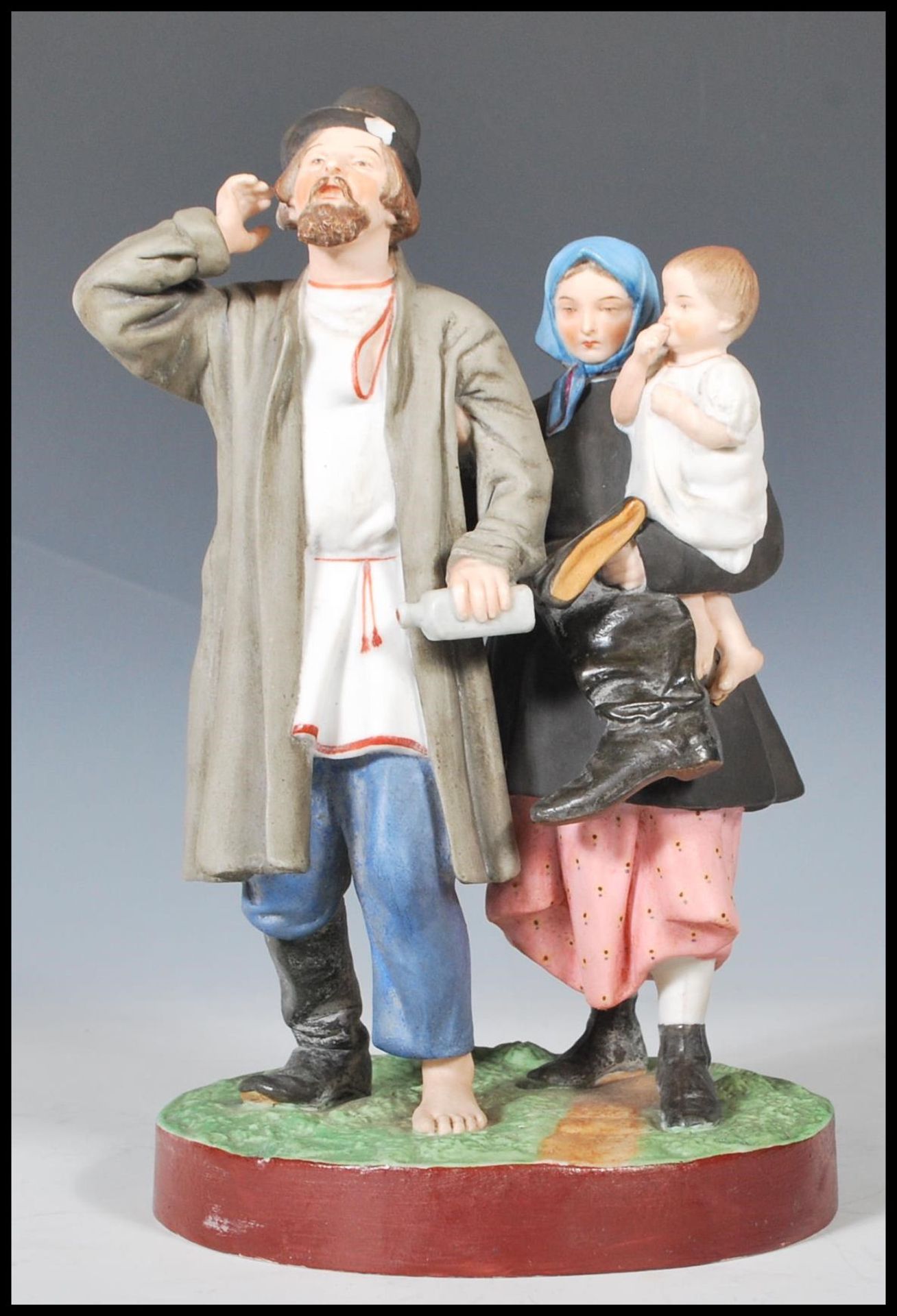 A 19th Century Russian Gardner bisque figurine group depicting a man with one boot and a bottle in