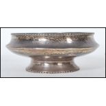 An early 20th Century silver hallmarked footed bowl with a hammered finish set with a George II
