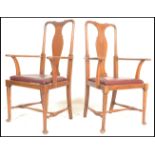 A pair of Edwardian oak Queen Anne elbow dining chairs being raised on cabriole legs with pad feet