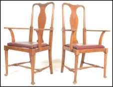 A pair of Edwardian oak Queen Anne elbow dining chairs being raised on cabriole legs with pad feet