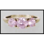 A hallmarked 14ct yellow gold ring set with a central pink stone flanked by two smaller pink stones.