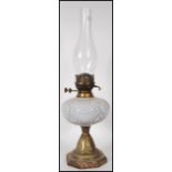 A Victorian 19th century oil lamp having a central white glass reservoir and glass flue all raised