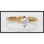 A hallmarked 9ct yellow gold single solitaire white stone ring on a split mount. English hallmarks