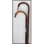 Two 20th Century walking stick canes with bamboo shafts and crook handles both terminating in silver