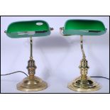 Two vintage 20th Century banker's desk lamps both raised on stepped round plinth bases, with