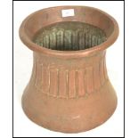 An early 20th Century Arts and Crafts hand worked copper planter on waisted cylindrical form, the