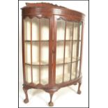 A 1920's bow front - demi lune Queen Anne mahogany display cabinet. Raised on claw and ball feet