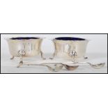 A pair of silver hallmarked table condiments complete with the blue glass liners and hallmarked