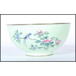 A Chinese enamel pedestal bowl on apple green ground, decorated peonies and butterfly, with a