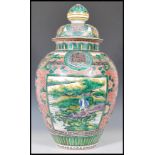A late 19th Century Chinese lidded urn vase of large tapering form being hand painted and