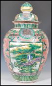 A late 19th Century Chinese lidded urn vase of large tapering form being hand painted and