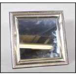 A 20th Century silver framed easel back mirror having repousse decoration borders to the frame,