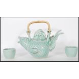 A 20th Century Oriental Chinese teapot in the form of a goldfish having a green glaze and bamboo