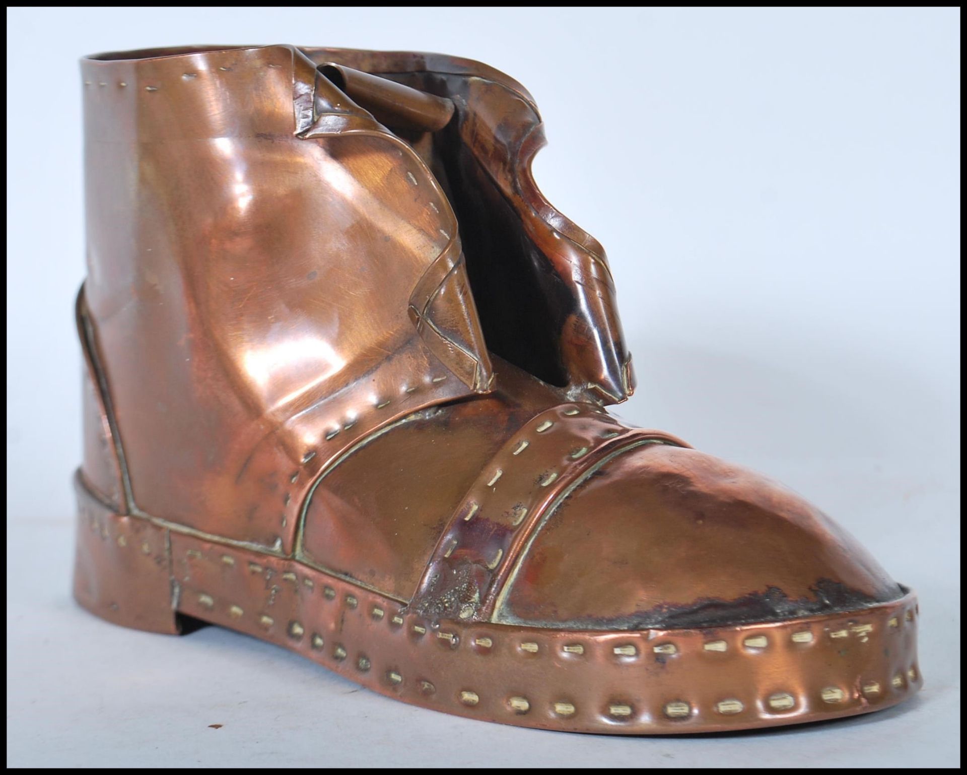 An early 20th Century Arts and Crafts copper hobnail boot having hand beaten decoration. Measures
