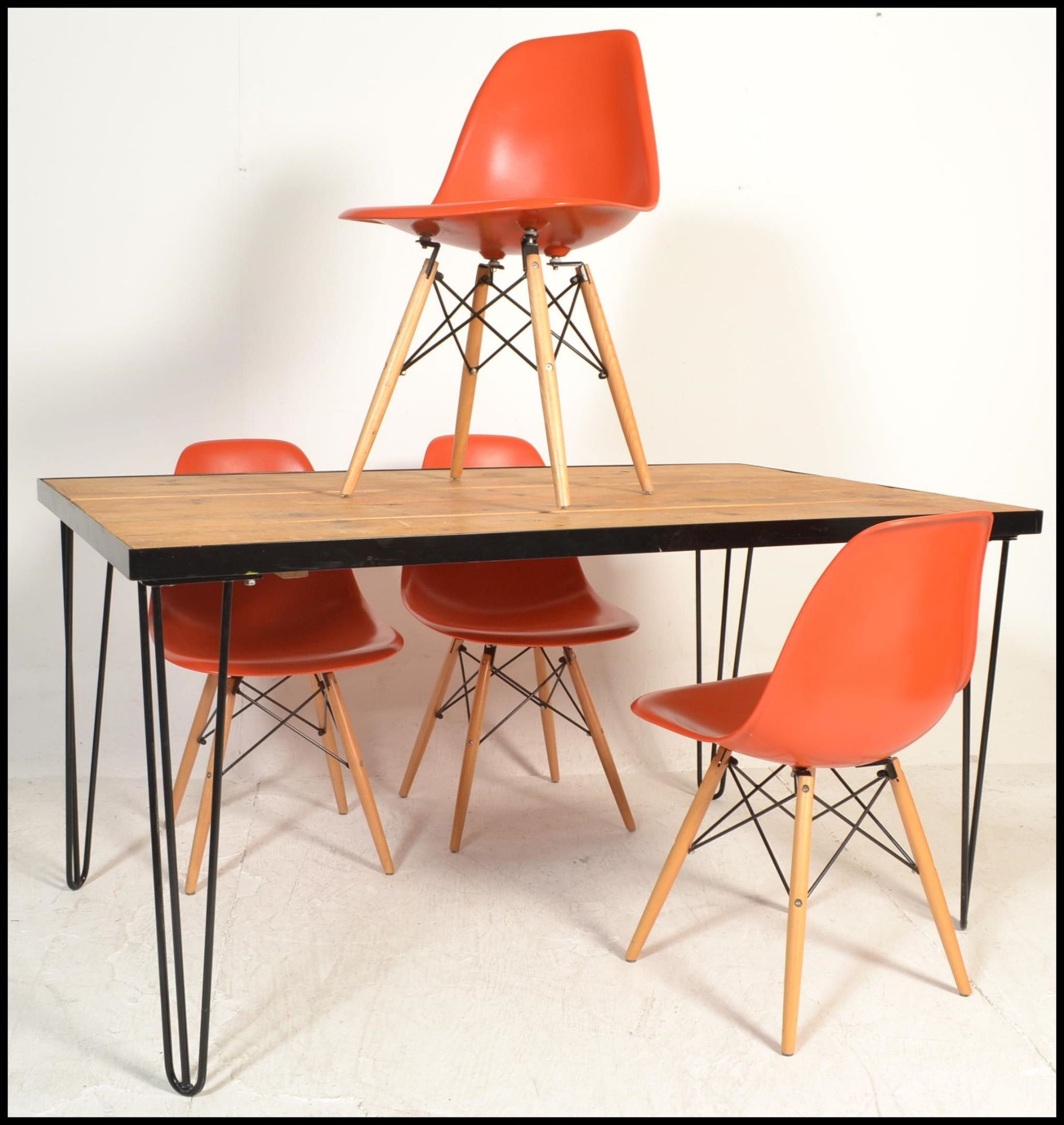 A retro style metal framed plank top dining table raised on hairpin upright supports in a black