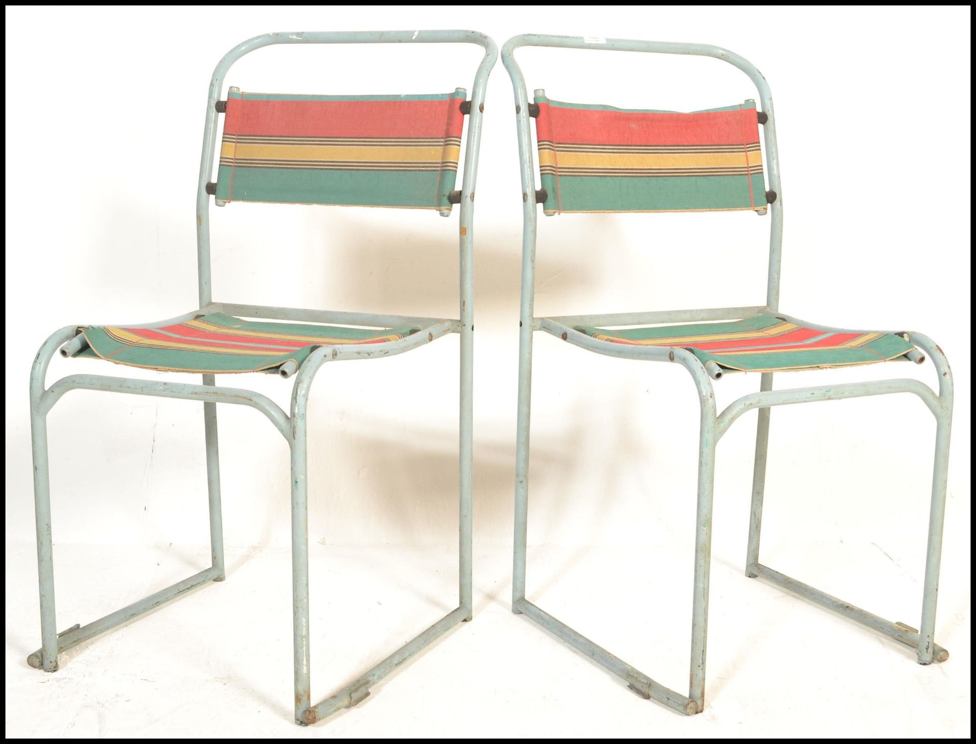 A pair of vintage mid 20th Century metal tubular village hall dispersal chairs, upholstered with a