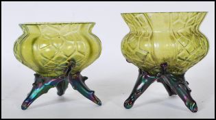 A pair of early 20th Century pressed green glass vases of bulbous forms raised on tripod