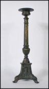 An antique style cast bronze candlestick raised on a tripod base having scrolled acanthus leaf