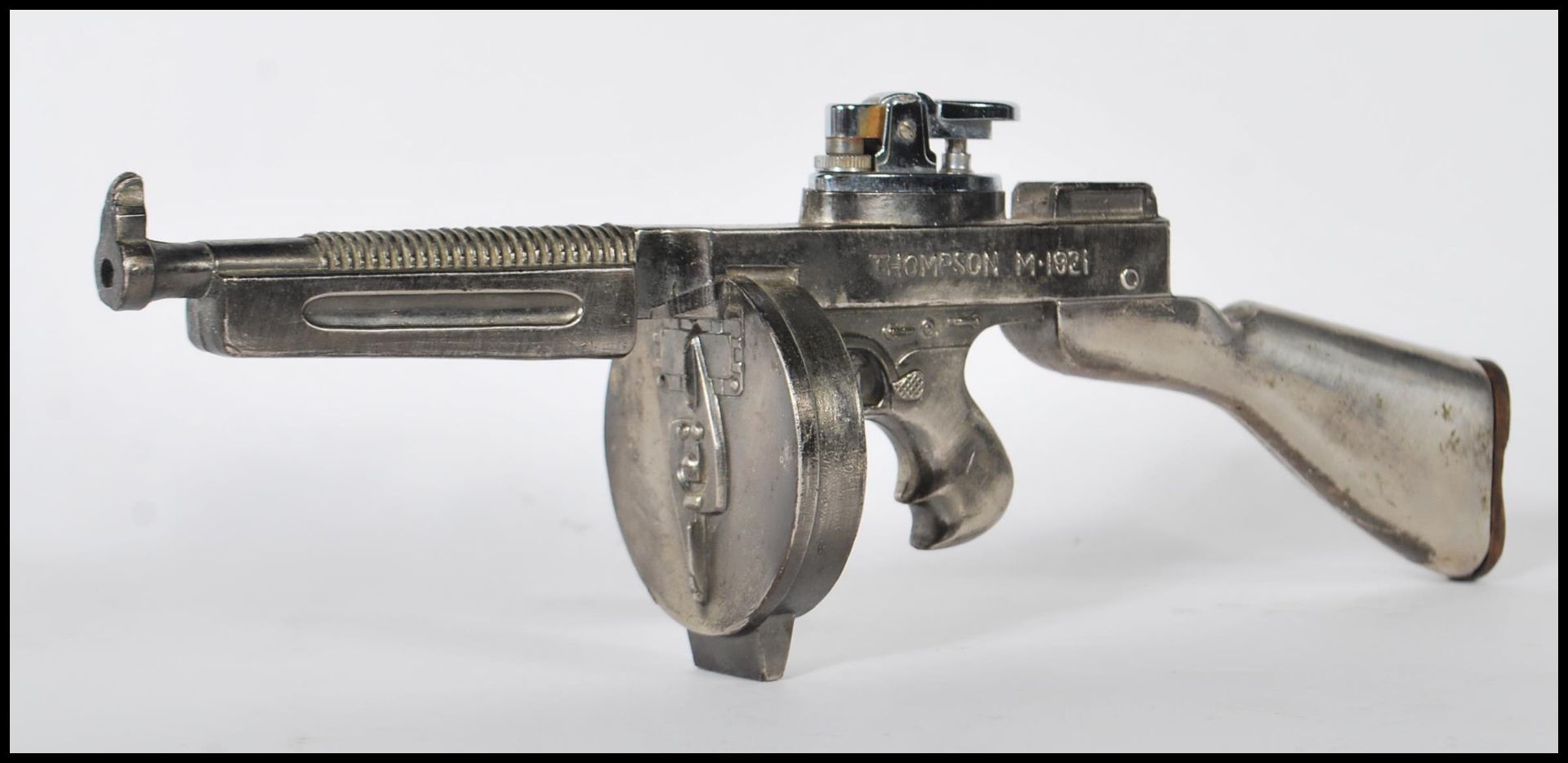 A vintage mid 20th Century table lighter in the form of a Thompson M.1921 submachine gun, being