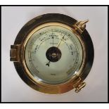 A contemporary 20th Century brass cased wall mounted ships barometer in the form of a porthole.