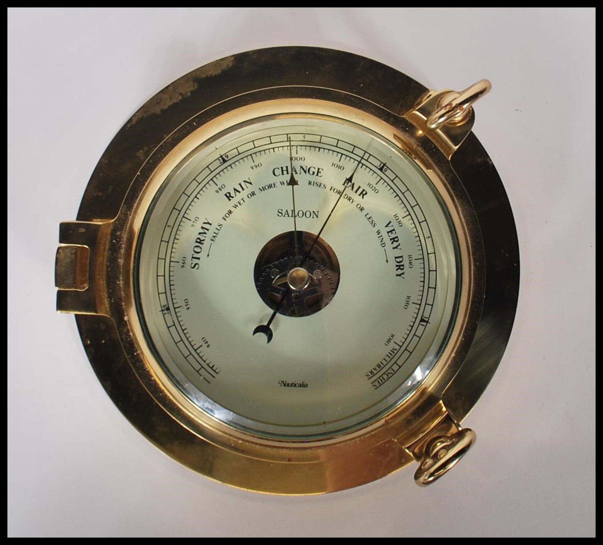 A contemporary 20th Century brass cased wall mounted ships barometer in the form of a porthole.