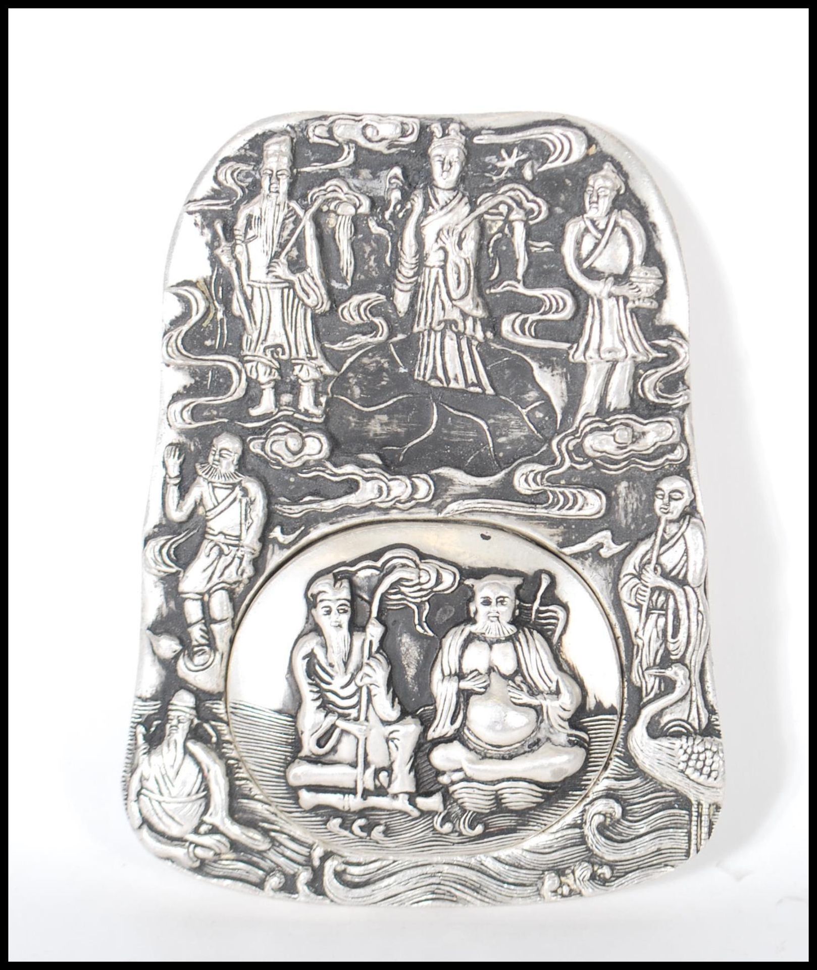 A Chinese white silver inkwell of ingot form, cast in relief with elders and Crane's central