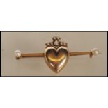 An 20th Century unmarked 9ct gold bar brooch having a central heart motif with a bow to the top, set