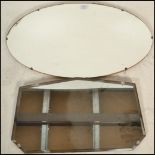 Two vintage mid 20th Century frameless mirrors to include an oval shaped mirror with bevelled