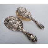 A silver hallmarked dressing table hair brush and matching hand mirror, the pair in relief depicting