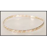 A hallmarked 9ct gold three tone twist design bangle bracelet. Hallmarked London (date marks